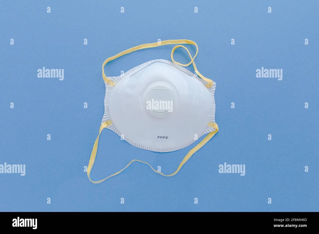 White FFP2,  N95  Industrial Respirator  filter Safety mask isolated on blue background. Protection from bacterias and virus,  included Covid-19 Stock Photo