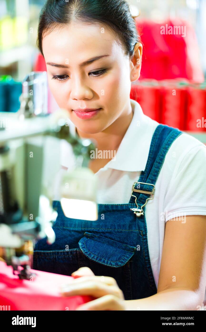 Seamstress or worker in a chinese factory sewing with a industrial sewing machine, she is very accurate Stock Photo