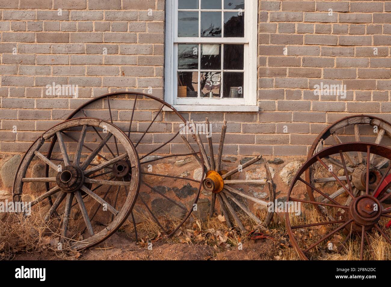 Old wagon wheels leaing up against a brick building, This is the Place