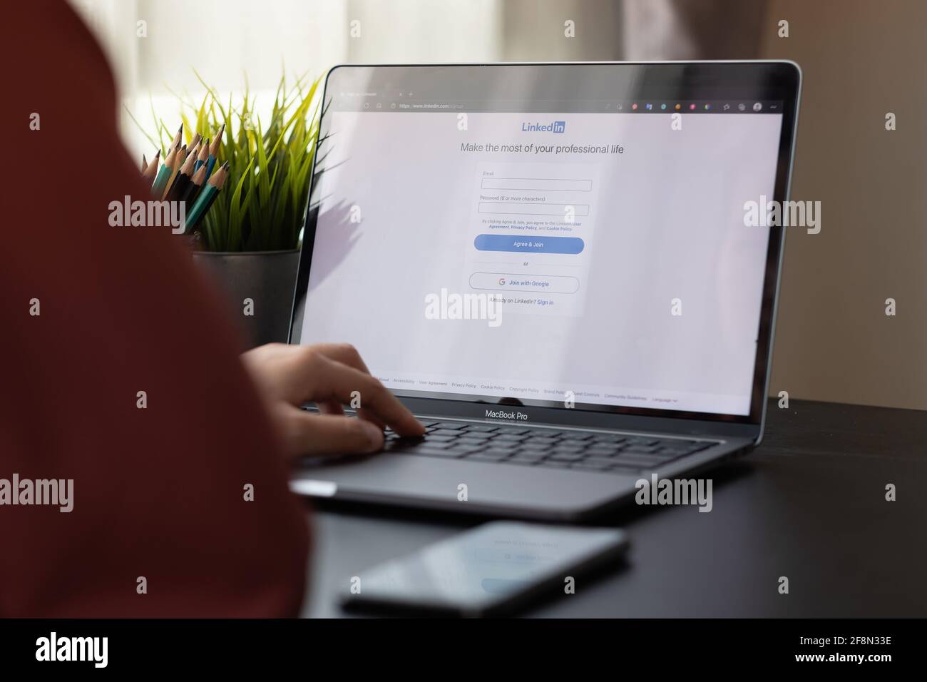 CHIANG MAI, THAILAND, APR 10, 2021 : A woman using macbook pro with LinkedIn on the screen.LinkedIn is a photo-sharing web Stock Photo