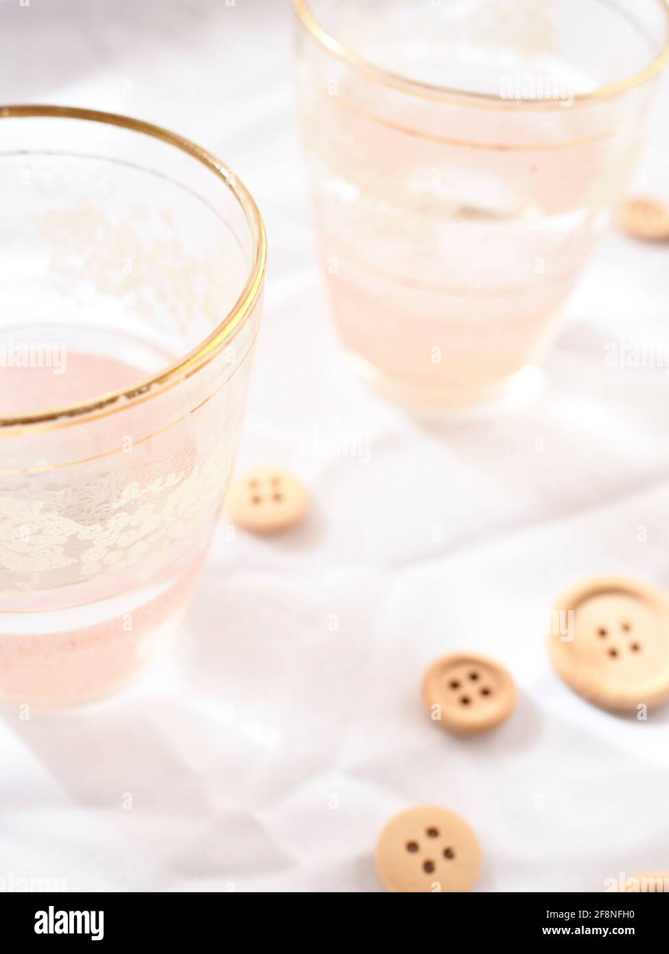 Pretty pink glasses and wooden buttons on a bright white background. Stock Photo