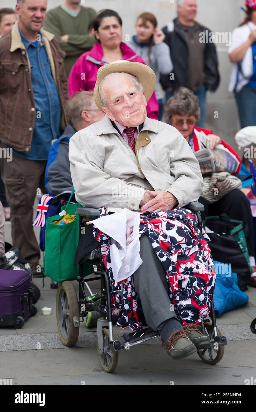A man in a wheelchair wearing a Prince Philip mask part of a large crowd of people gathered in Trafalgar Square to watch a giant television showing Her Royal Highness Queen Elizabeth ii, Diamond Jubilee celebrations. Trafalgar Square, London, UK.  5 Jun 2012 Stock Photo