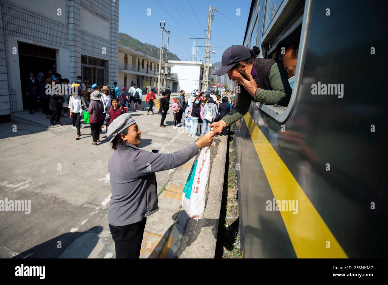 (210415) -- XICHANG, April 15, 2021 (Xinhua) -- A passenger of Yi ethnic group makes a deal with a peddler when the 5633 train stopping at a station in southwest China's Sichuan Province, April 11, 2021. As modern high-speed trains shoot past new stations throughout China, a pair of slow-speed trains still run through Daliang Mountains. The 5633/5634 trains run between Puxiong and Panzhihua of Sichuan Province with an average speed less than 40 km per hour. The journey with 26 stations in between takes eleven hours and four minutes, with the ticket prices ranging from 2 yuan to 25.5 yuan(abo Stock Photo