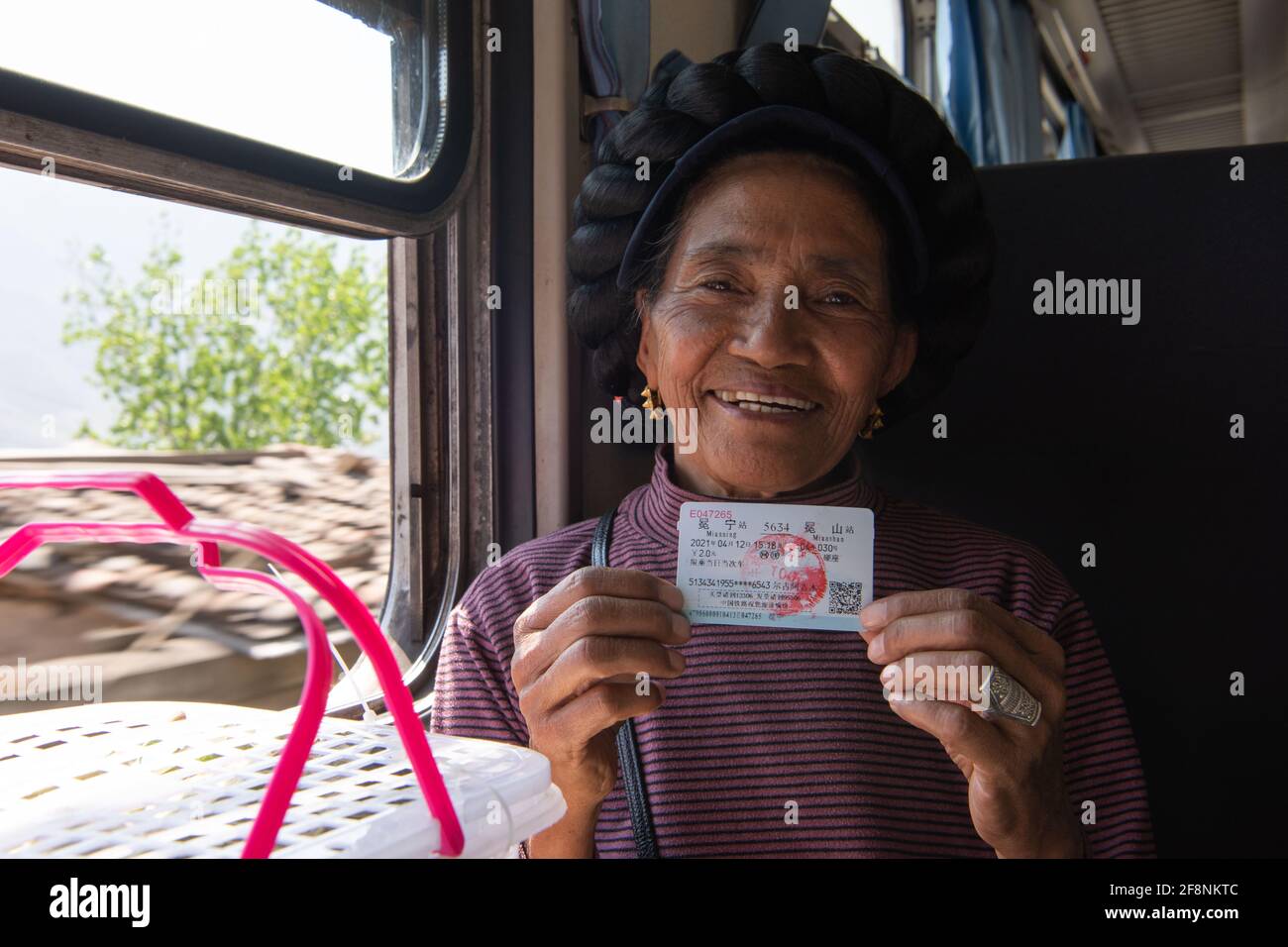 (210415) -- XICHANG, April 15, 2021 (Xinhua) -- A passenger shows her ticket on the 5634 train in southwest China's Sichuan Province, April 12, 2021. As modern high-speed trains shoot past new stations throughout China, a pair of slow-speed trains still run through Daliang Mountains. The 5633/5634 trains run between Puxiong and Panzhihua of Sichuan Province with an average speed less than 40 km per hour. The journey with 26 stations in between takes eleven hours and four minutes, with the ticket prices ranging from 2 yuan to 25.5 yuan(about 0.3-3.9 U.S. dollars). The slow-speed trains sen Stock Photo