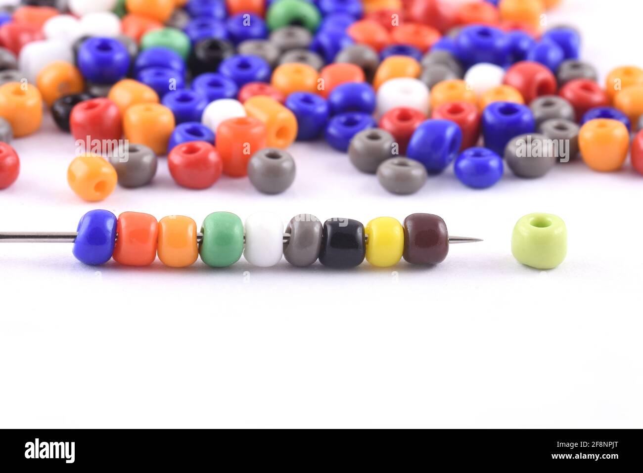 Multi colored Beads spread on white background with needle Beads with needle Close up, macro, bead necklace Stock Photo