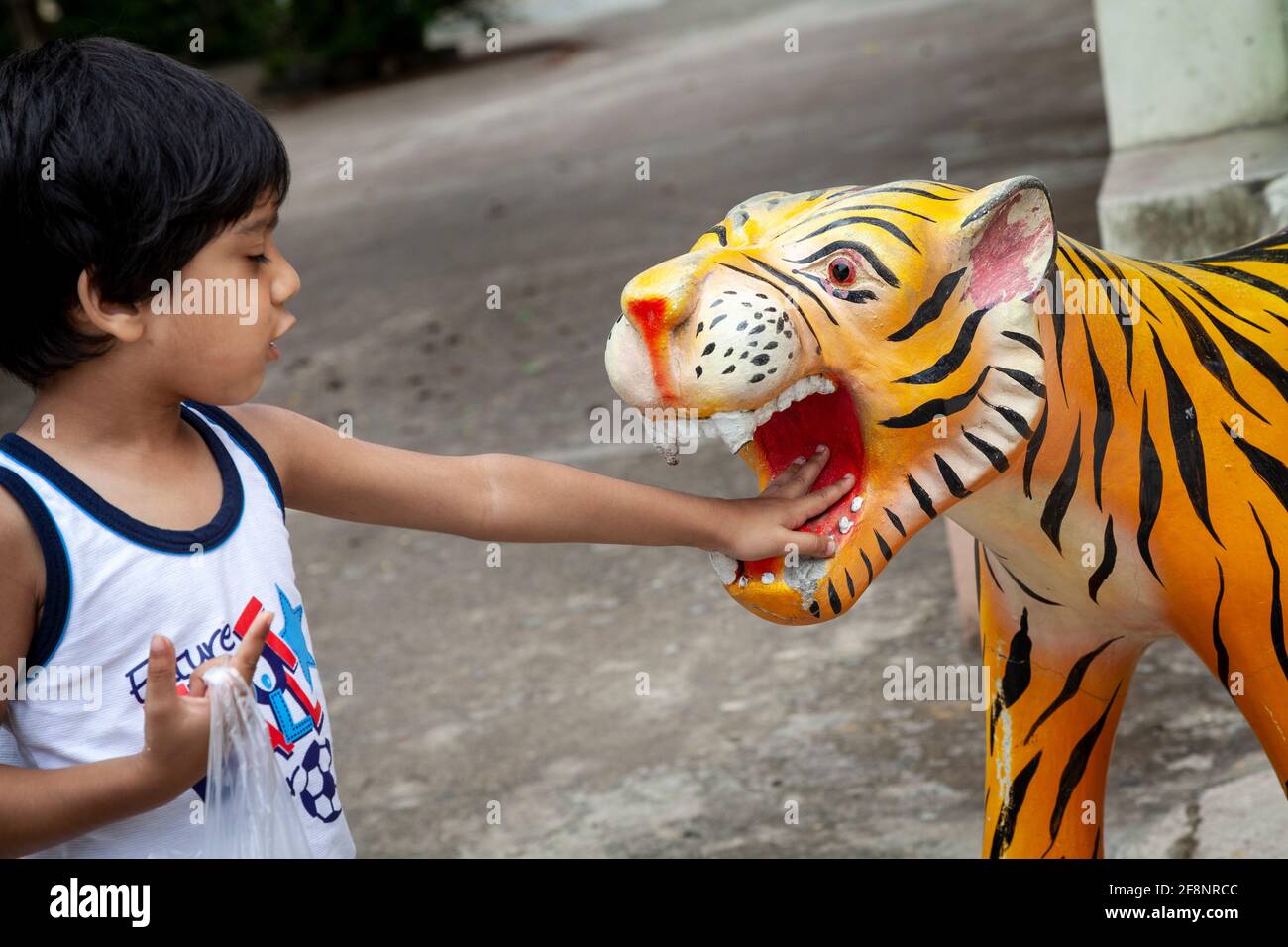 View of a young boy putting his hand inside the mouth of a lion statue at the famous Big Buddha place in Pattaya, Thailand. Stock Photo