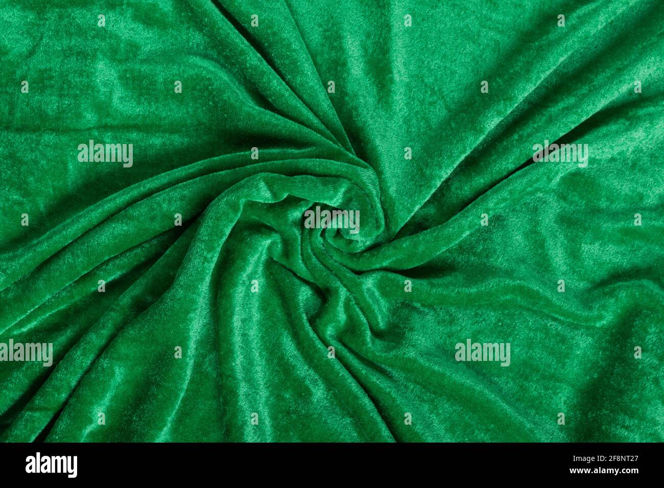 Colored green textile satin fabric folded in folds and waves with highlights and texture shimmers in the light Stock Photo