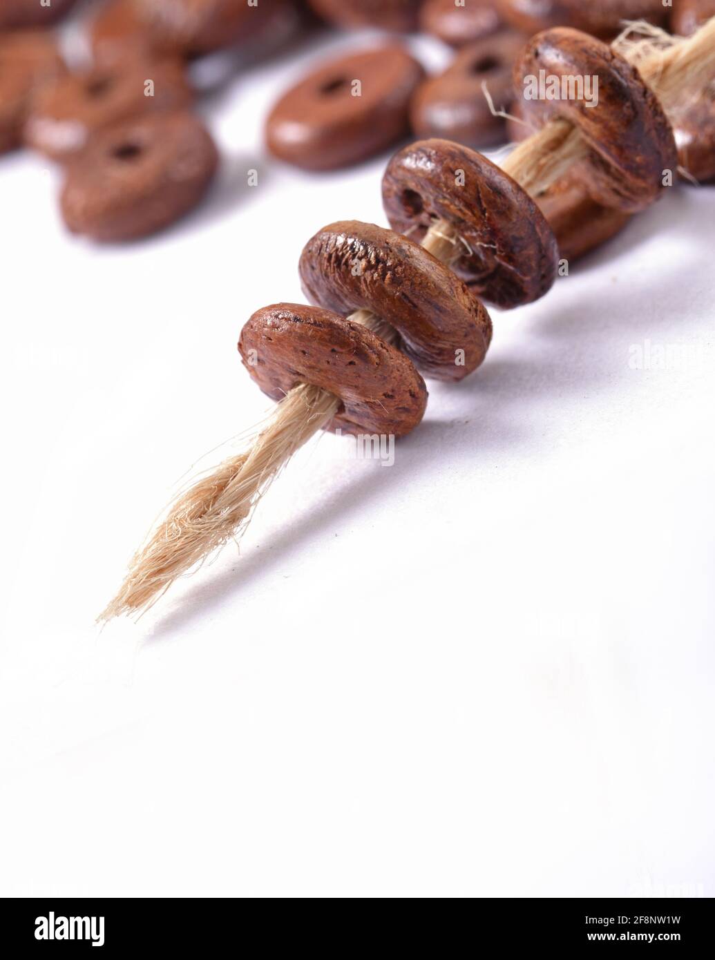 Wooden beads with natural jute string Twine Rope on white background Close up, macro Stock Photo