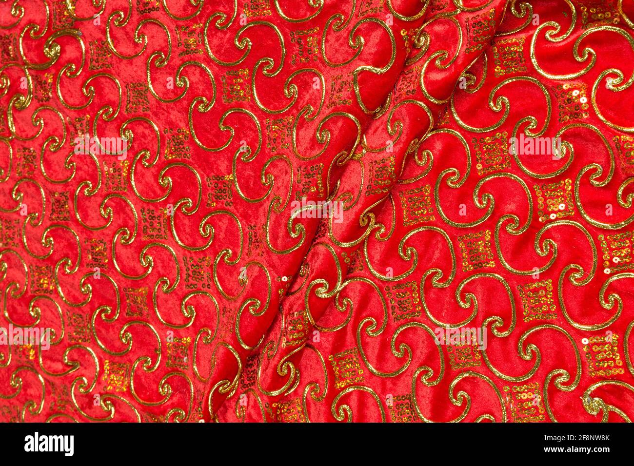 Colored red textile satin fabric folded in folds and waves with ...