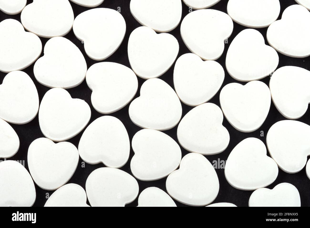 Heart shaped pills on a black background Medicines that help people Stock Photo