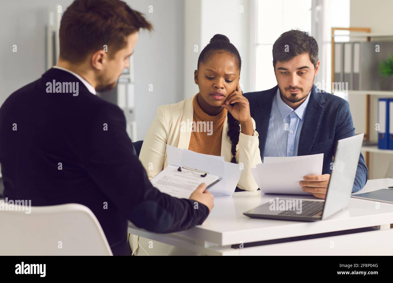 Married couple carefully examines an important contract while sitting in a meeting at a bank office. Stock Photo