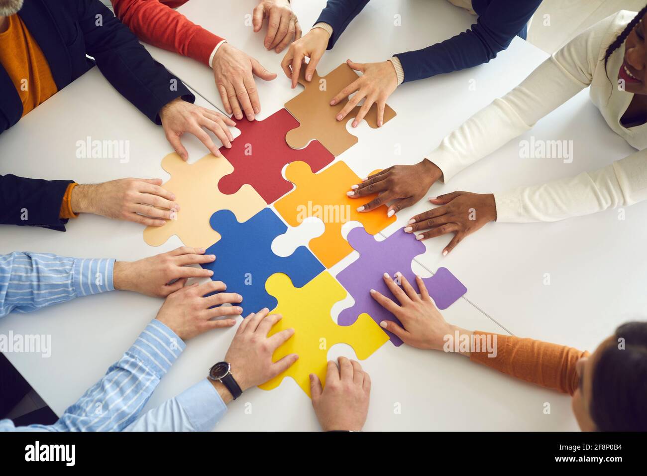 Office team assembling jigsaw puzzle pieces on table top view on hands  Stock Photo - Alamy