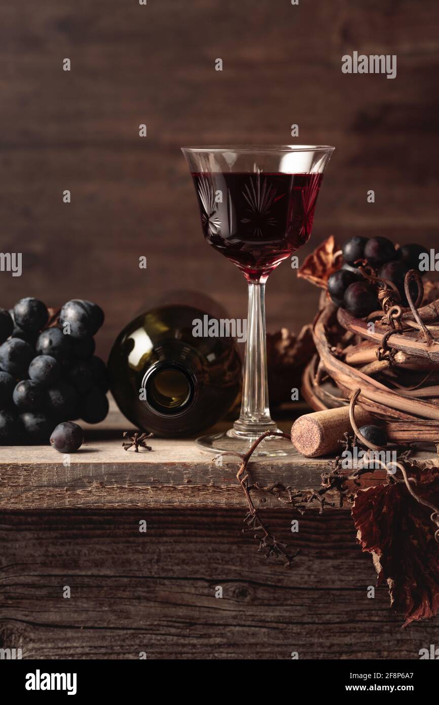 Crystal glass and bottle of port red wine with grapes on an old wooden ...