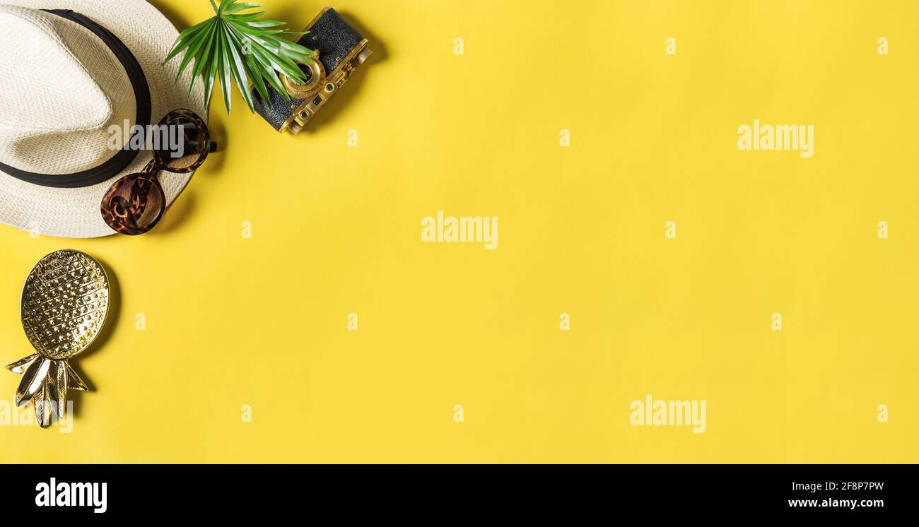 Travler flat lay. Sunglasses, palm leaf, photo camera, straw hat on yellow background Stock Photo