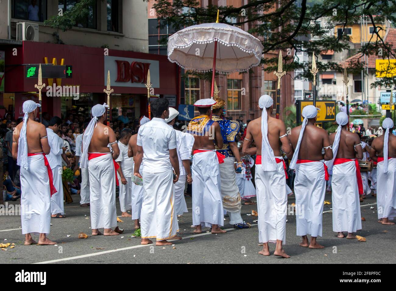 Spear Bearers surround a Buddhist Temple Custodian as he parades along a street in Kandy during the Day Perahera, the final event of Esala Perahera. Stock Photo
