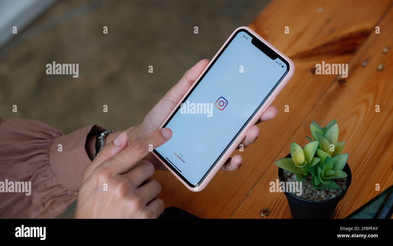 CHIANG MAI, THAILAND - MAR 21 2021 : Woman hand holding iphone with logo of instagram application. Instagram is largest and most popular photograph Stock Photo