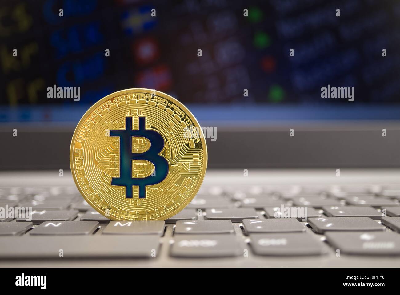 Bitcoin on the computer keyboard in front of the monitors with currency ...