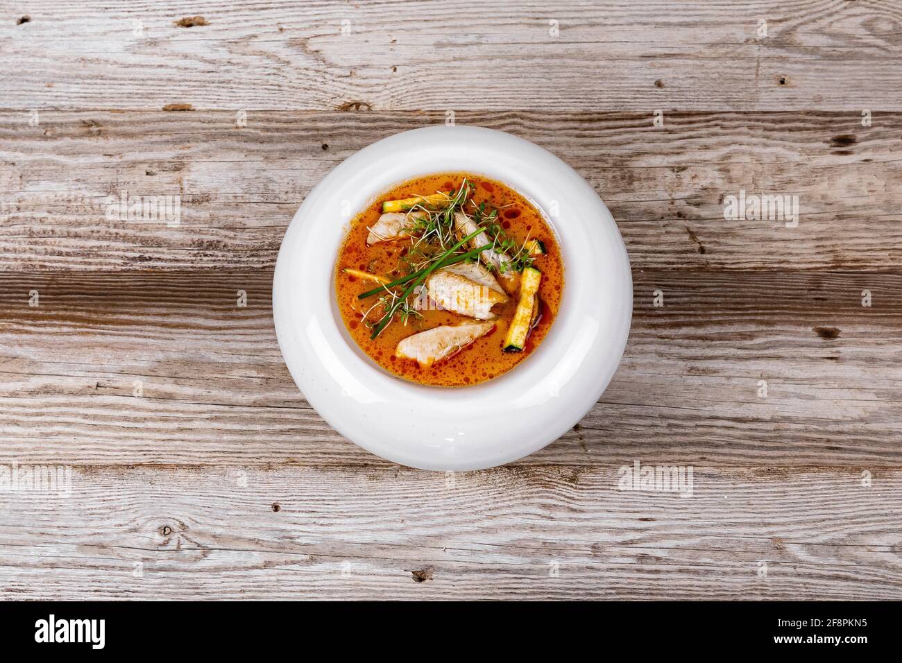 Tom Yum Soup with Chicken on wooden background in white plate