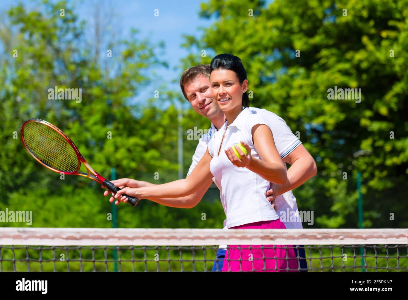 Man, tennis sport teacher, teaching woman how to play the racket sport
