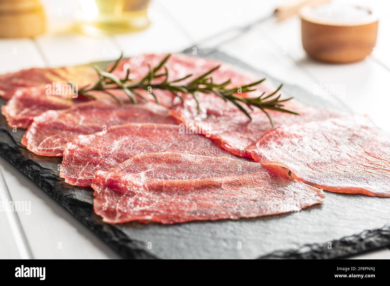 Sliced carpaccio. Raw beef meat on black cutting board. Stock Photo