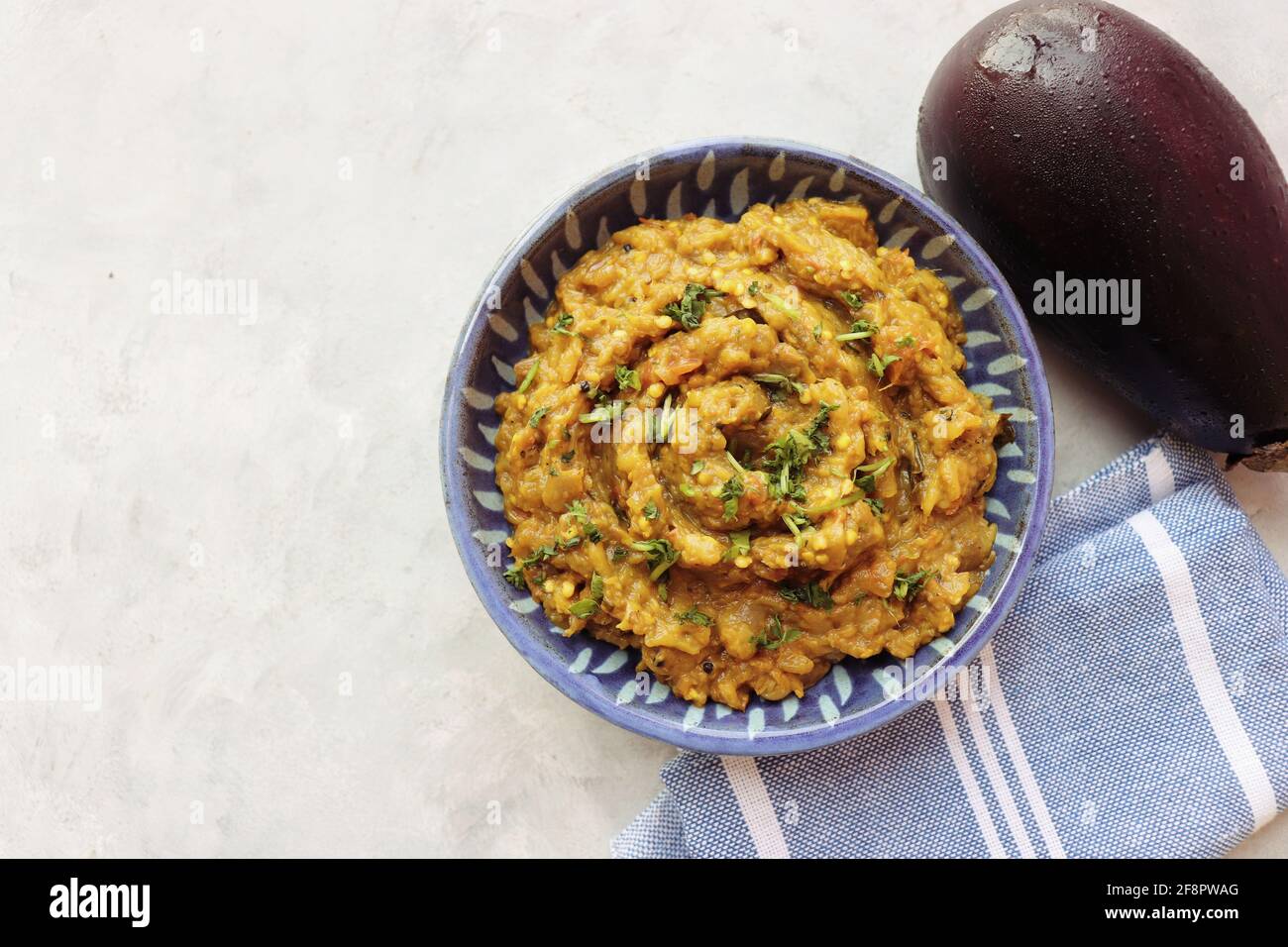 Baigan Bharta, also called Vangyache Bharit in Marathi. It is a roasted eggplant curry. Brinjal chutney. served in a wooden bowl with roti. Stock Photo