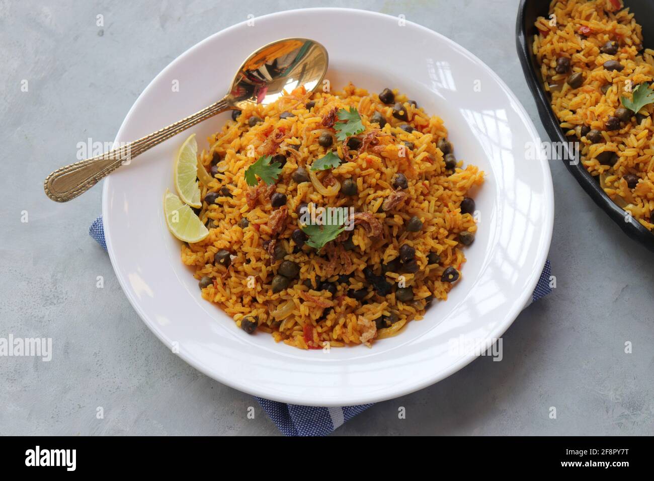 Indian cuisine - Chickpeas Biryani, chole Pulao. Garnished with fried onion, chopped coriander, and lemon wedges. Kala chana biryani. copy space Stock Photo