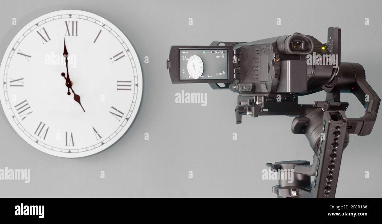 The camera on the gimbal shoots the clock. Gray background. Stock Photo