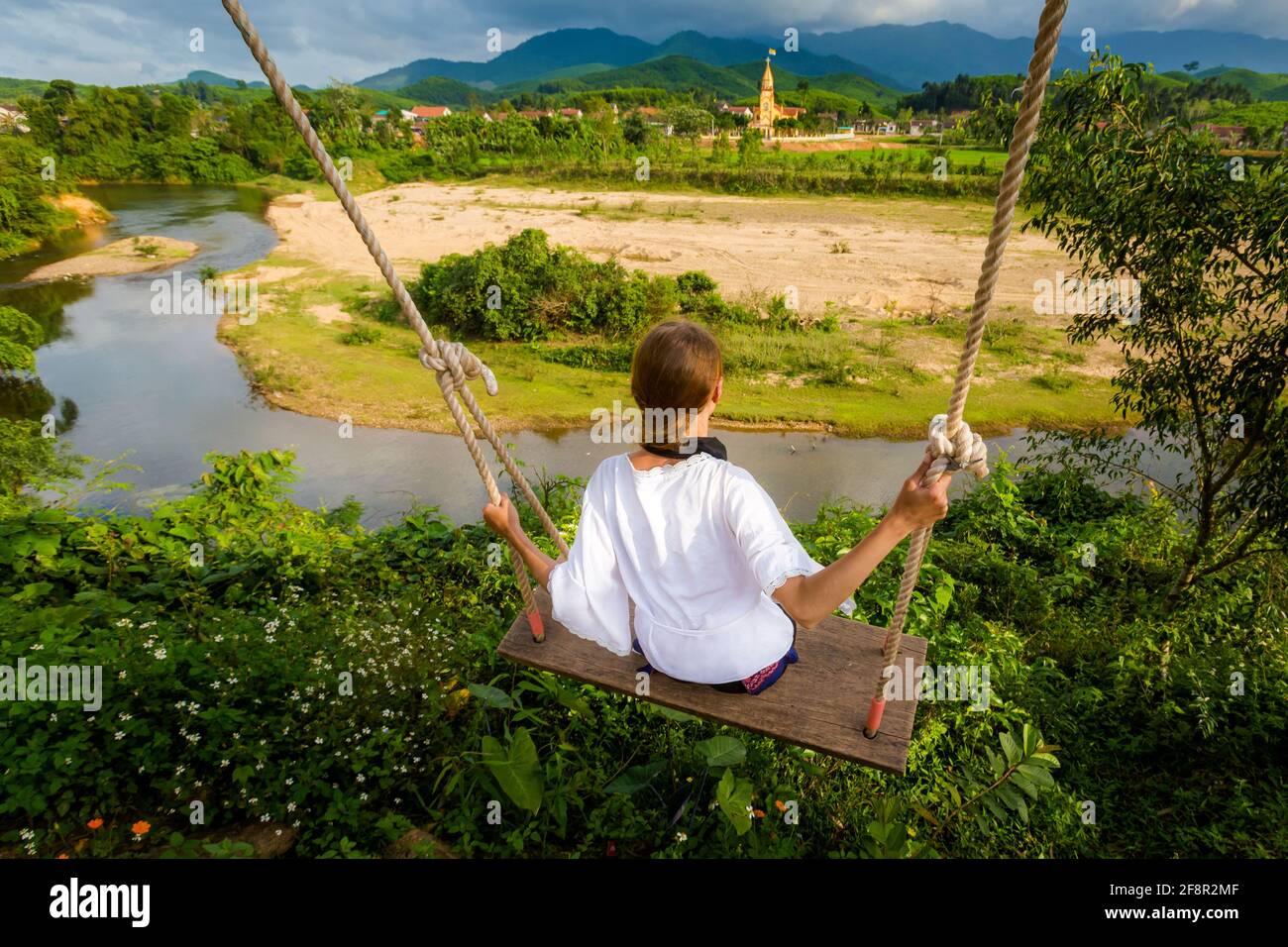 Beautiful young caucasian tourist on a swing in National Park Phong Nha Ke Bang, Vietnam. Rural scenery photo taken in south east Asia - one of the mo Stock Photo