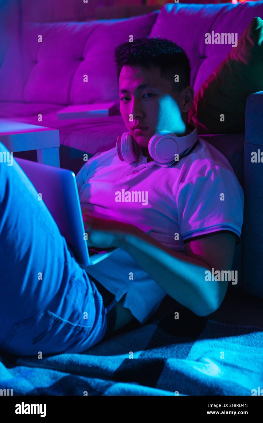 Young Korean man using laptop at home interior in gradient pink blue neon  light Stock Photo - Alamy