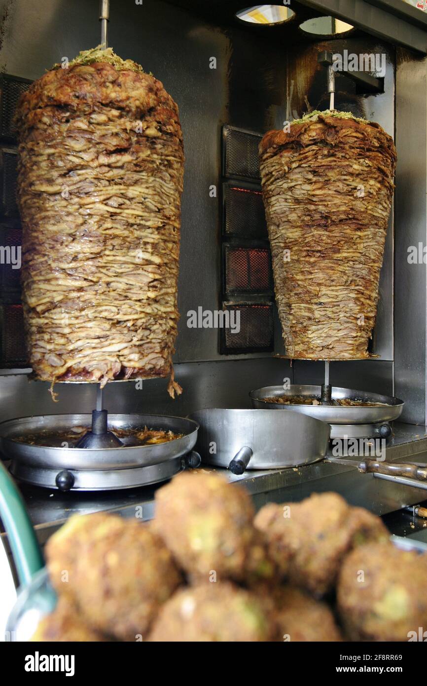 Doner Kebap at the rotisserie, falafel in the foreground Stock Photo
