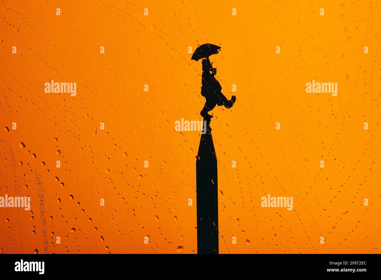 April fool's day with a silhouette of a clown on top of a tower on orange background with drops Stock Photo