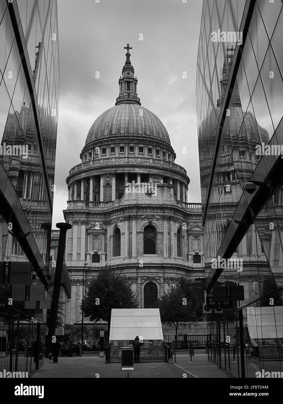 St. Paul’s Cathedral reflected to triplicate by the glass sides of nearby buildings. A silhouetted person in the foreground gives a sense of scale. Stock Photo