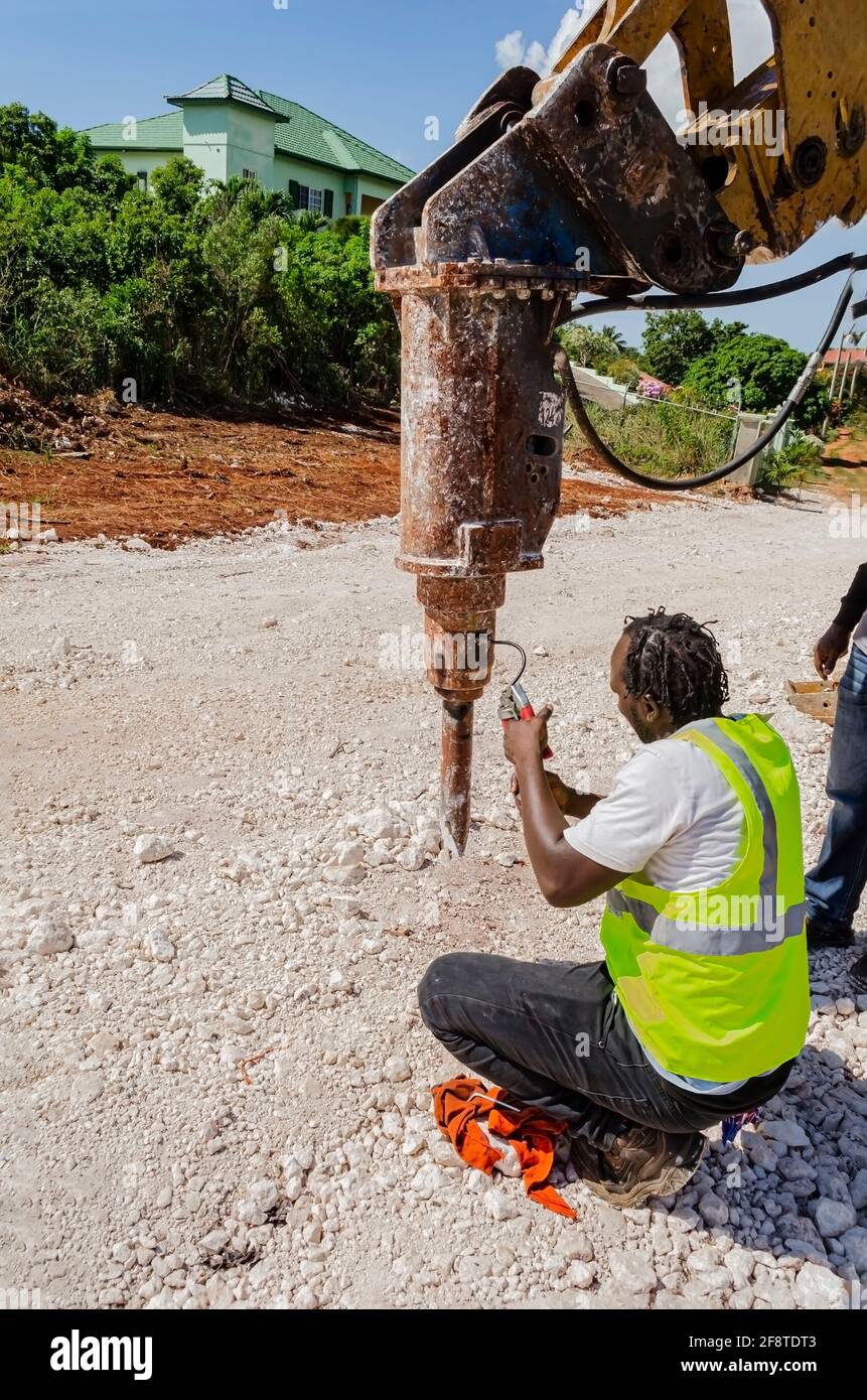 A jackhammer that is being suspended from the arm of a backhoe is being
