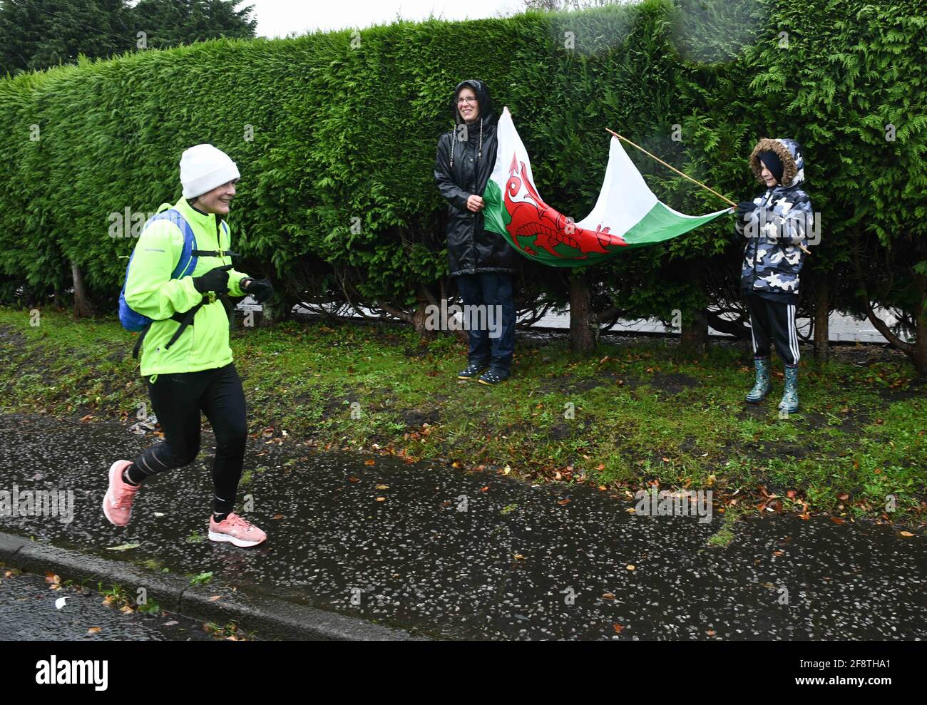 Swansea, Wales, 4th October 2020. UK Weather : Supporters with a Welsh flag brave the heavy rain in Swansea, south Wales to come out and cheer on a runner taking part in the Virtual London Marathon.   Photo credit : Robert Melen. Stock Photo