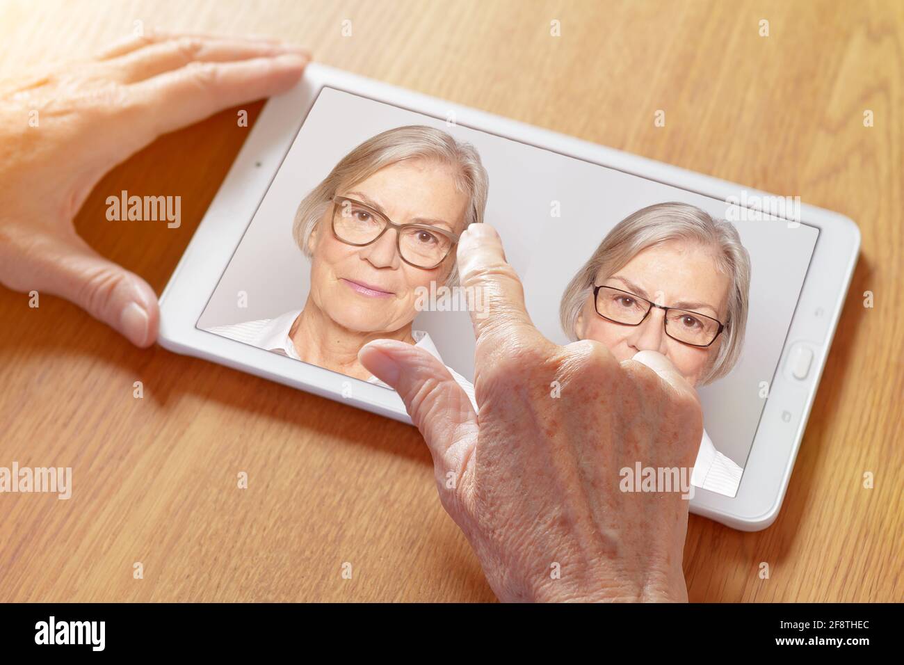 Shopping eyeglasses online concept: hands of a senior woman choosing her new glasses at home on a tablet computer. Stock Photo