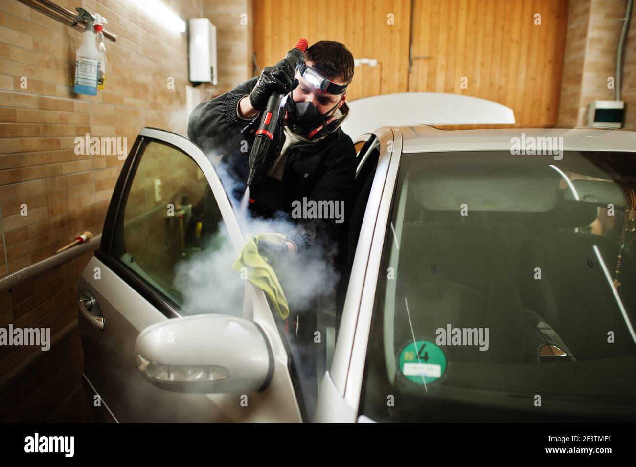 Man in uniform and respirator, worker of car wash center, cleaning