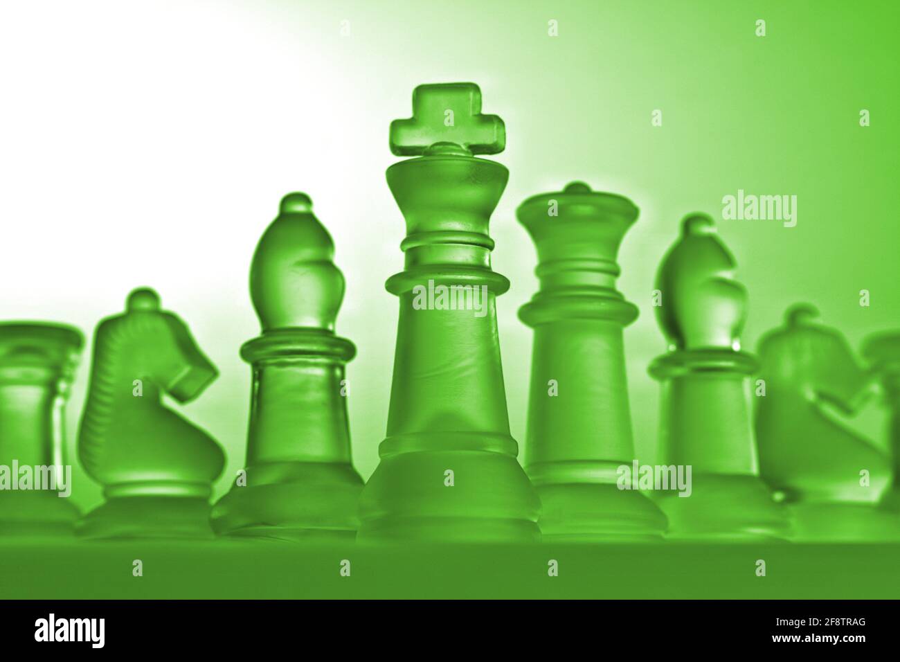 Deutschland. 11th Apr, 2021. Symbolic chess pieces of a chess game made of  glass with a neutral background. Detail of some white figures with a green  light mood from a slight frog's