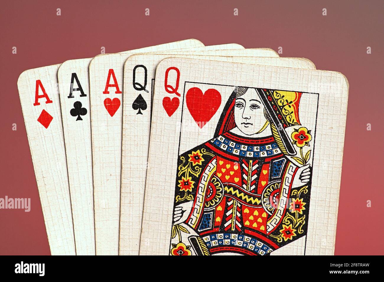 Deutschland. 09th Apr, 2021. Playing cards of a poker hand from an old card game, French Hand, with a full house of three aces and two queens, held by one hand in the gate against a red background. | usage worldwide Credit: dpa/Alamy Live News Stock Photo