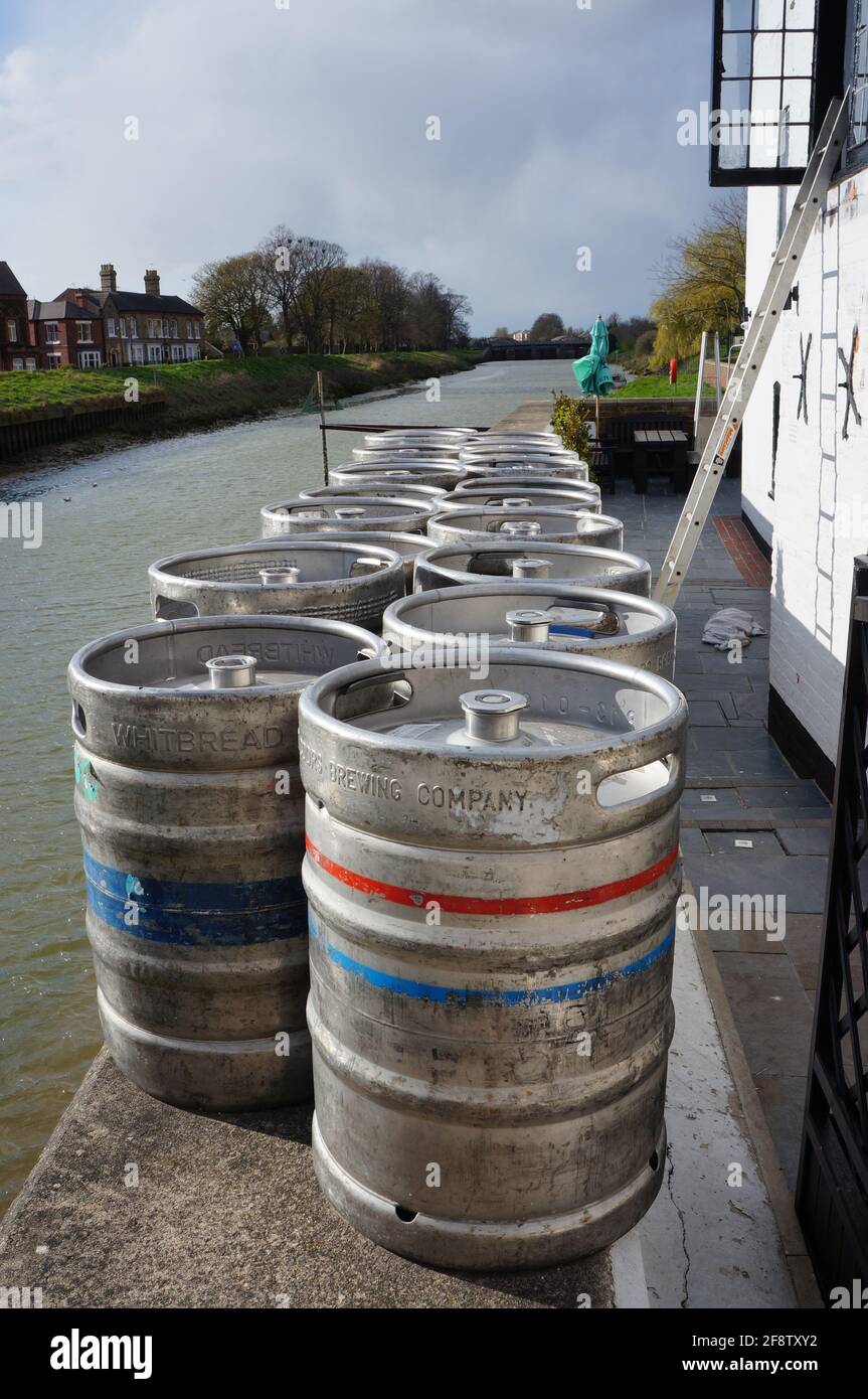 Metal beer barrels lined up outside a pub beside the River Witham