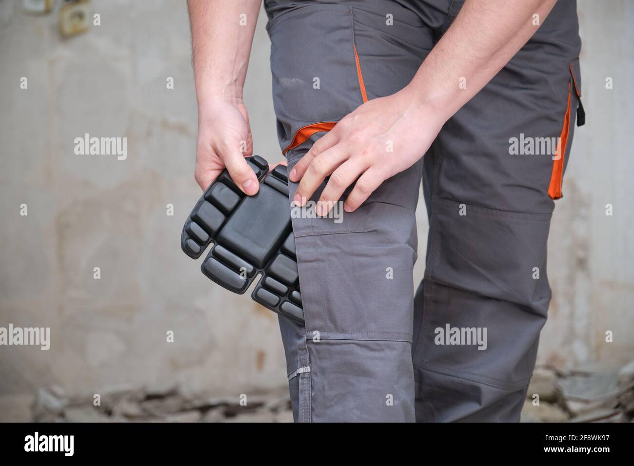 Unrecognizable builder wearing knee protection pads to work in a construction. Safety at work. Stock Photo