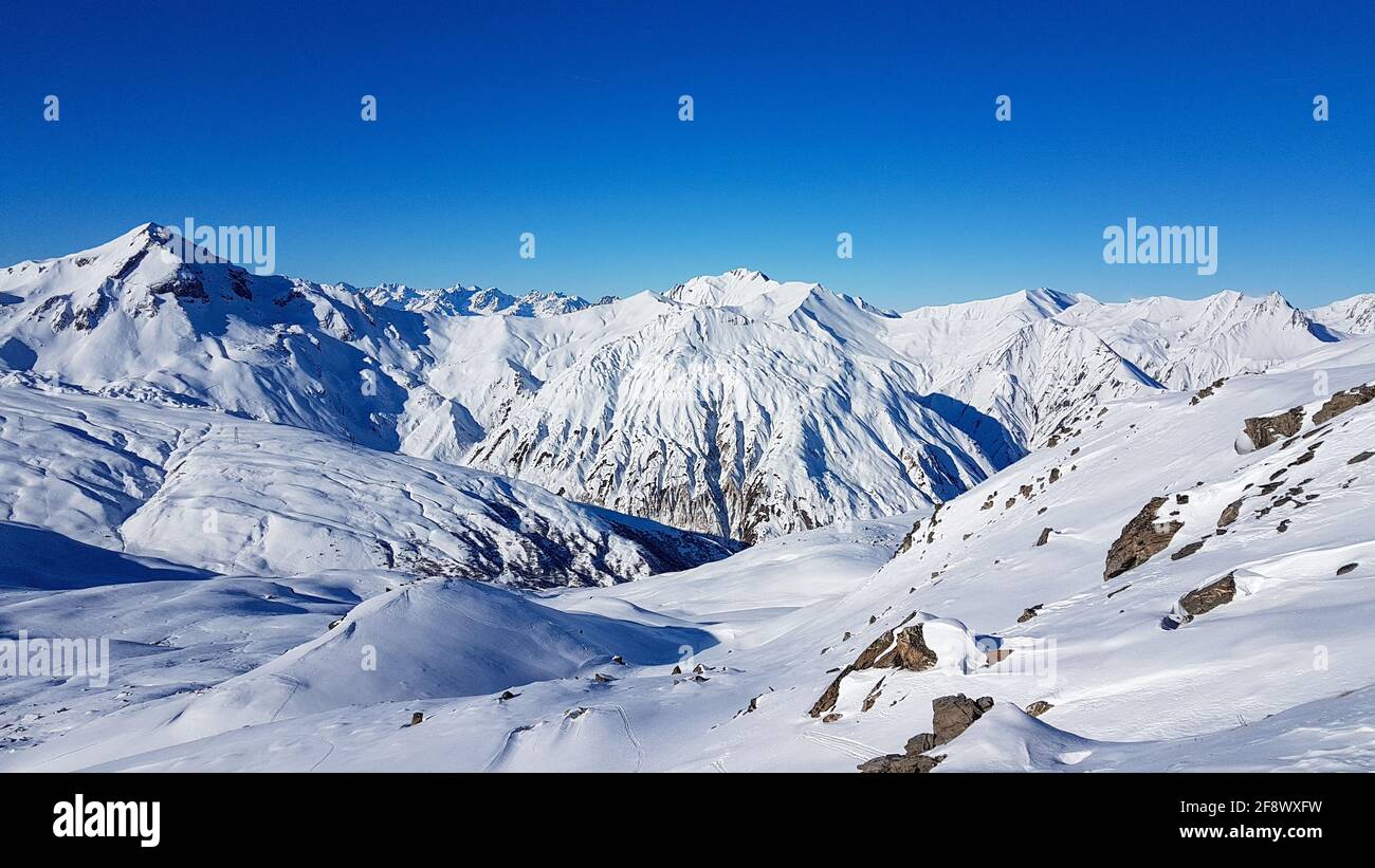 Sunny view over the peaks of white mountains of the French Alps from the ski area Les Trois Valless with clear blue sky Stock Photo