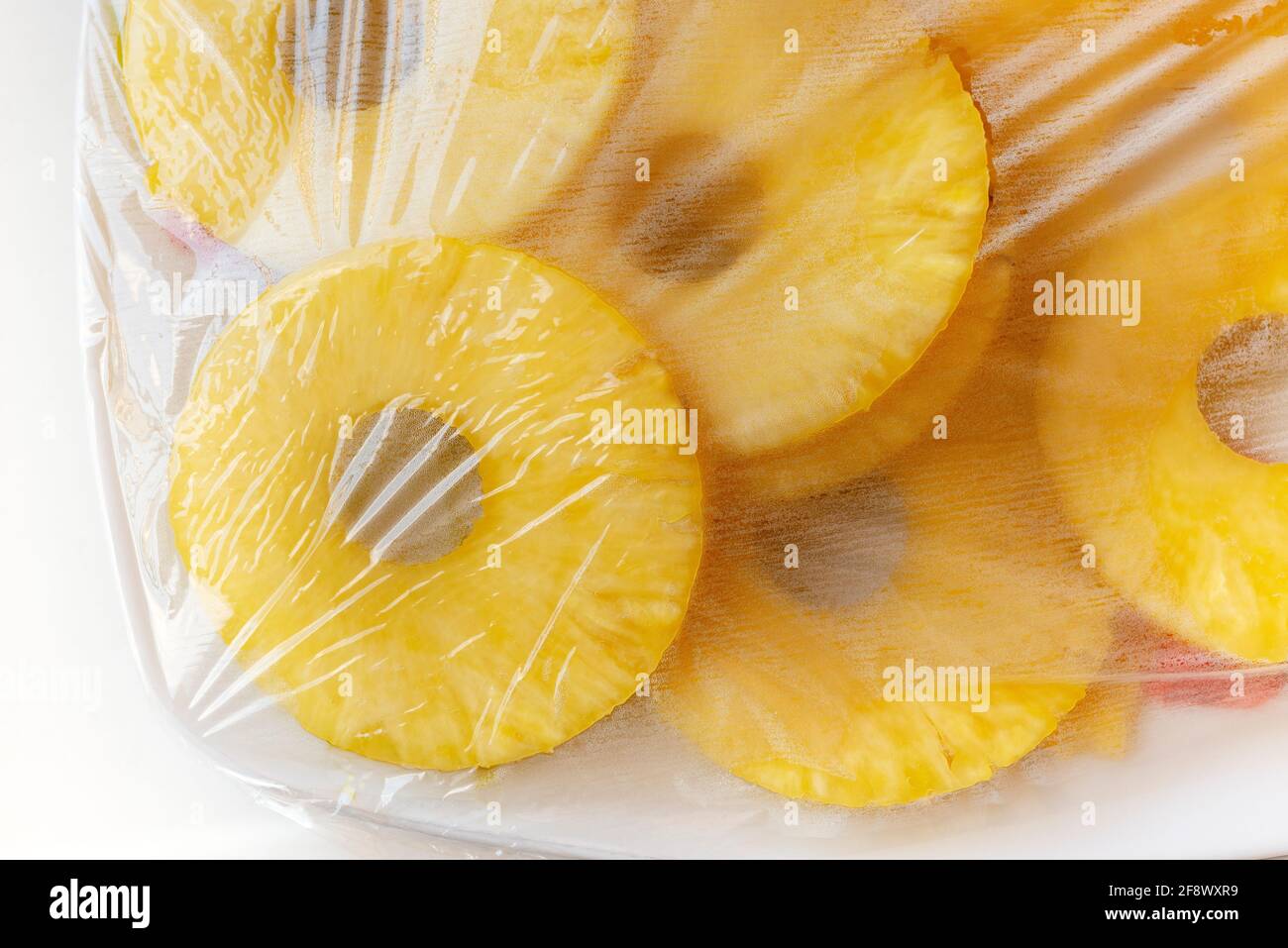 Slices of Fresh Pineapple Ananas Covered With Plastic Wrap Stock Photo