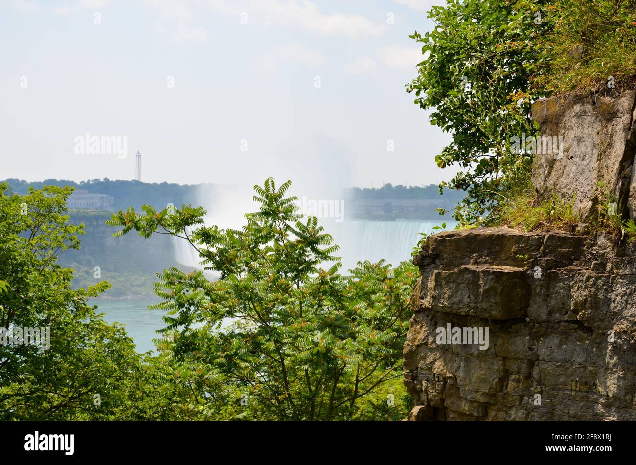 View from a rock plato between rocks and trees to the Canadian Niagara Falls in sunny weather Stock Photo