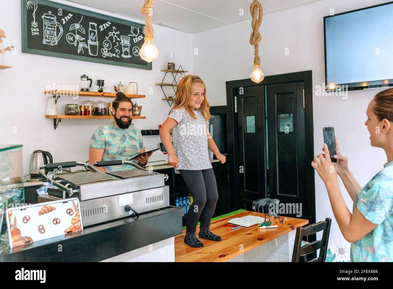 Parents taking care of their daughter while working in a coffee shop. Stock Photo