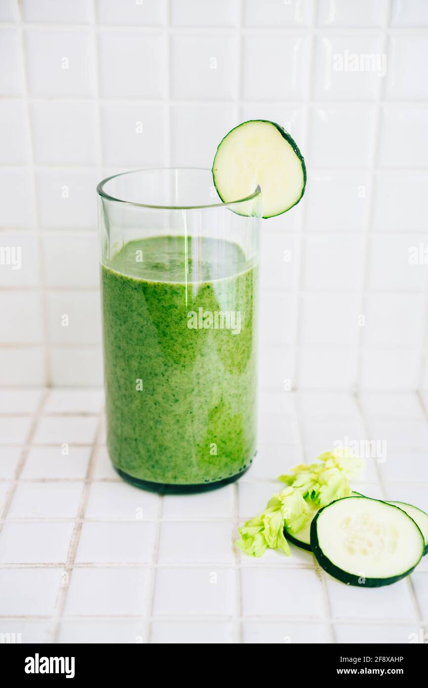 Green smoothie with celery and cucumber in crystal glass on a white tile background Stock Photo