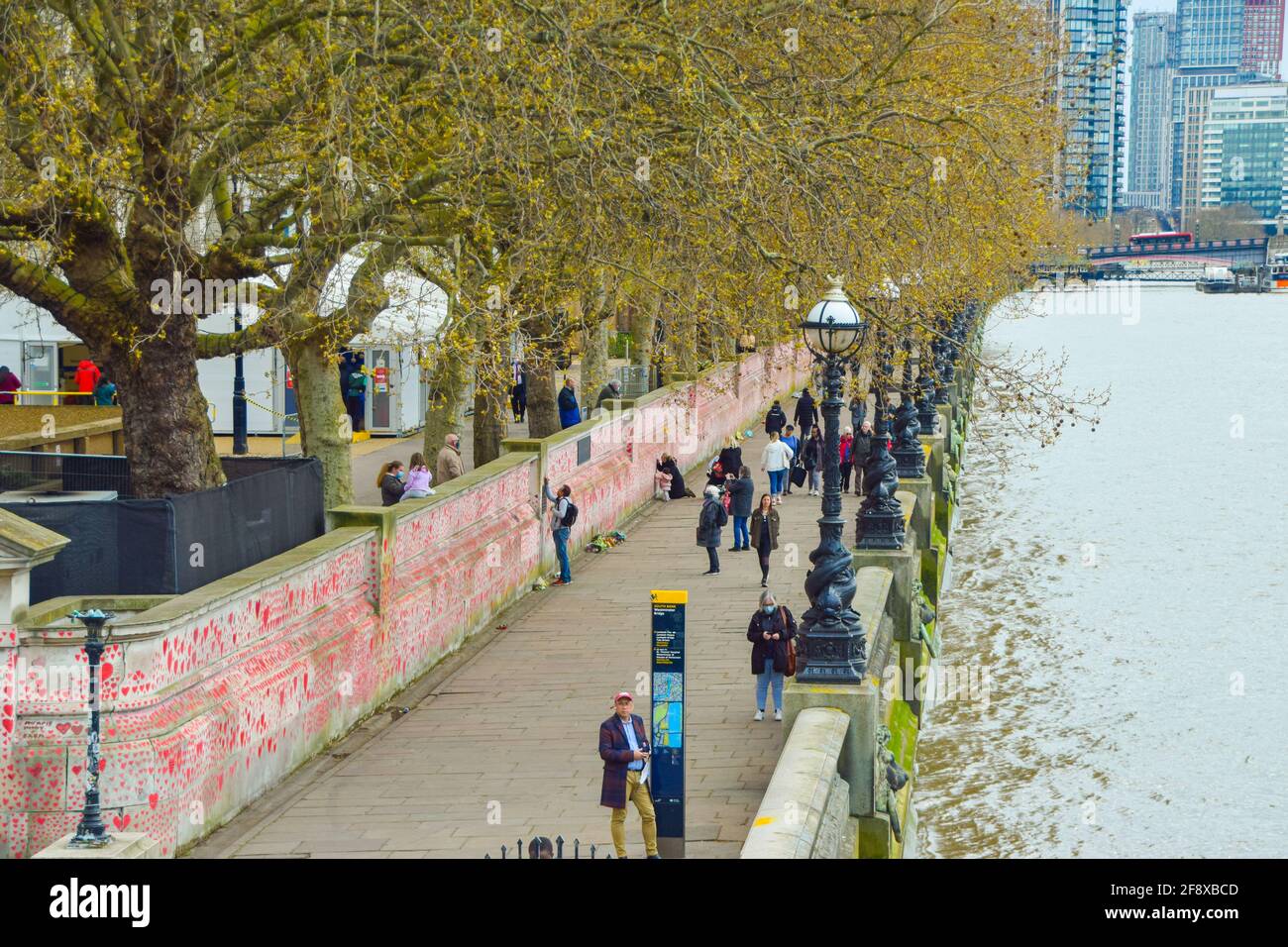 London, United Kingdom. 13th April 2021. People visiting the National Covid Memorial Wall. Around 150,000 hearts have been painted by volunteers and members of the public, one for each Covid-19 victim in the UK to date, on the wall outside St Thomas' Hospital opposite Houses Of Parliament. Stock Photo