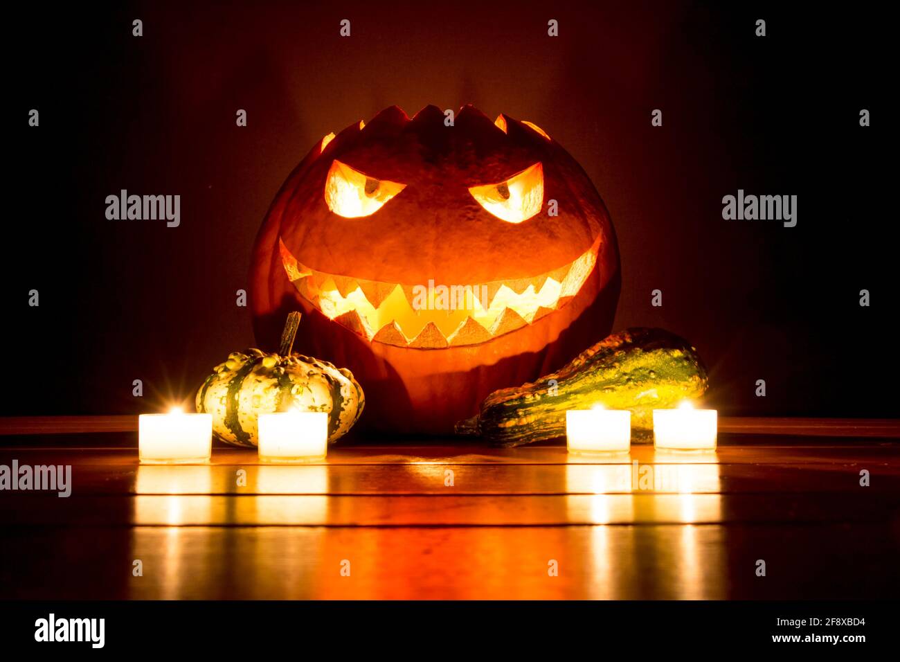 Spooky carved halloween pumpkin with candles and small pumpkins. Big