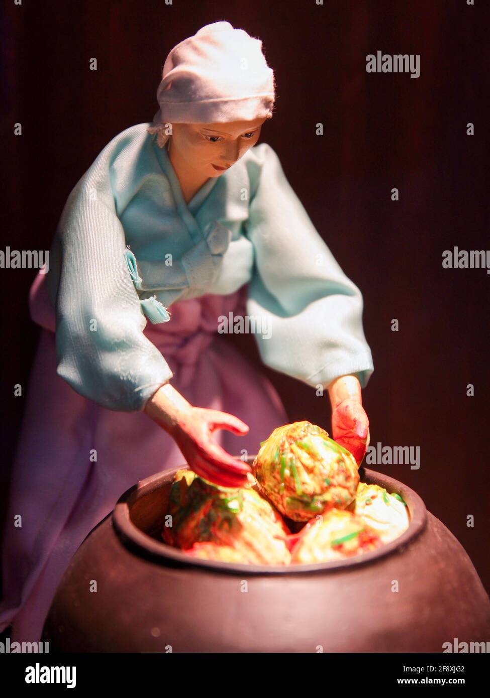 Diorama of a woman loading cabbage, vegetables in a clay pot for kimchi
