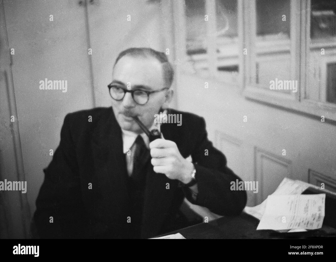 1950s, historical, a company manager sitting at his desk in his office smoking his pipe, relaxing, having a break from his work, England, UK. In this era, the vast majority of the UK population smoked, with 8 out of 10 men being smokers. It was a cheap, legal and socially acceptable habit and that included smoking in the workplace. Overwhelming evidence of the harmful effects of smoking tobacco and changes in society means that any form of smoking is now banned in all enclosed places of employment. Stock Photo