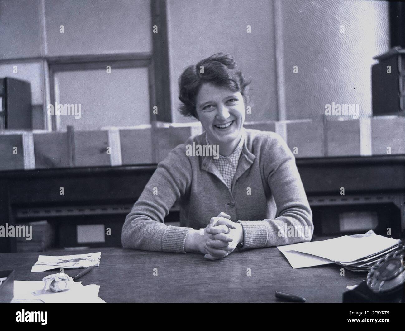 1950s, historical, a young female clerical worker sitting at a workspace for a picture in an office, with paperwork and a telephone of the era, England, UK. Stock Photo